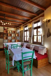 een eetkamer met tafels, stoelen en ramen bij Hotel Bineri in Gjirokastër