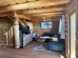 a living room in a log cabin with a couch and a television at Reimers Chalets Hochrindl in Hochrindl