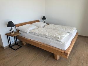 a wooden bed with white sheets and pillows on it at Reimers Chalets Hochrindl in Hochrindl