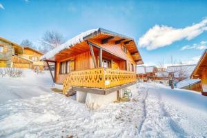 a wooden cabin with a snow covered porch in the snow at Chalet les Colchiques in La Toussuire