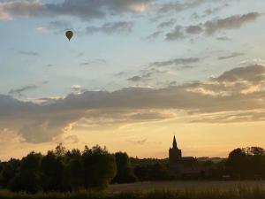 un globo de aire caliente volando en el cielo sobre una iglesia en Cottage chaleureux au cœur des Monts de Flandres, en Saint-Jans-Cappel