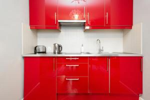 cocina roja con fregadero y armarios rojos en Stars Apartaments City Center by Renters, en Varsovia