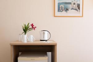 una mesa con una cafetera y flores en ella en CORFU MARIS BELLOS en Benitses