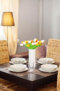 una mesa con platos y un jarrón de flores. en Stars Apartaments City Center by Renters, en Varsovia