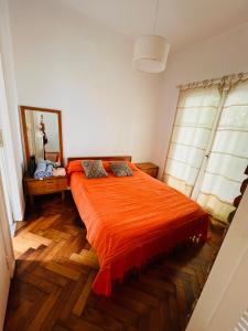 1 dormitorio con cama de color naranja y espejo en Hermoso Departamento en Belgrano R para 3 personas en Buenos Aires