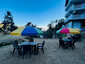 un grupo de mesas y sillas con sombrillas en la playa en THE FIG, en Mukteshwar