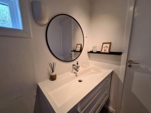 a bathroom with a white sink and a mirror at Summarhús29 in Tvøroyri