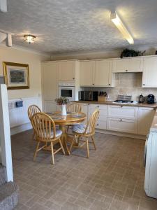 a kitchen with a wooden table and chairs and a counter at Beech View Cottage in Downham Market