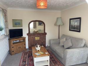 ein Wohnzimmer mit einem Sofa und einem TV in der Unterkunft Beech View Cottage in Downham Market