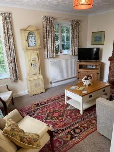 uma sala de estar com uma mesa e um relógio avô em Beech View Cottage em Downham Market