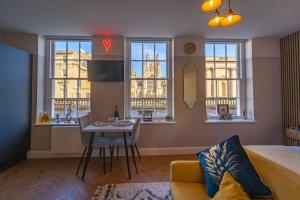 a living room with a couch and a table and windows at Abbey View studio central Bath in Bath