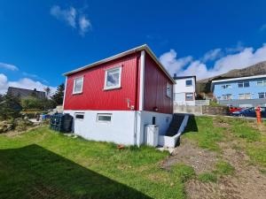uma casa vermelha e branca numa colina relvada em Summarhús29 em Tvøroyri
