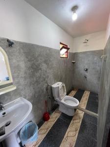 a bathroom with a white toilet and a sink at Jungle Villa in Ahangama