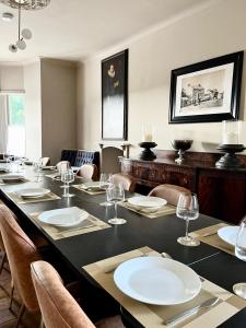 ein Esszimmer mit einem langen Tisch mit Tellern und Weingläsern in der Unterkunft Bodorgan Inn By Birch Stays in Bodorgan