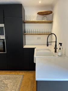 a kitchen with a sink and a black cabinet at Bodorgan Inn By Birch Stays in Bodorgan