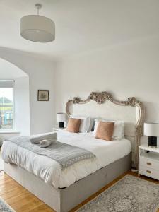 ein weißes Schlafzimmer mit einem großen Bett mit Kissen in der Unterkunft Bodorgan Inn By Birch Stays in Bodorgan