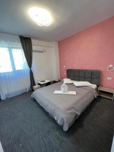 a bedroom with a large bed and a pink wall at Hotel AMA WORLD in Constanţa