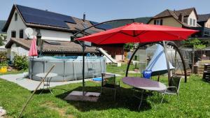 einen Hinterhof mit einem Pool und einem roten Regenschirm in der Unterkunft Mini Happy home in Reconvilier
