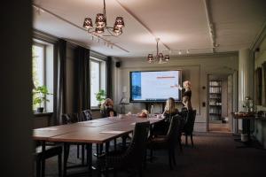 a woman giving a presentation in a room with a table at Åsby Hotell in Hallstahammar