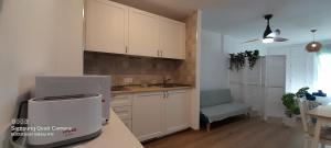 kuchnia z białymi szafkami, zlewem i krzesłem w obiekcie Loft 105 w Corralejo
