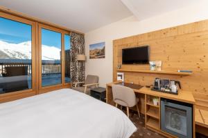 a bedroom with a bed and a desk with a television at Nira Alpina in Silvaplana