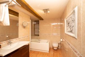 a bathroom with a sink and a tub and a toilet at Hôtel Lastiry in Sare