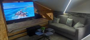 sala de estar con sofá y TV de pantalla plana en L'Esthélio Gîtes ou L'Esthélio Spa avec Jacuzzi et Sauna, en Ambérieu-en-Bugey