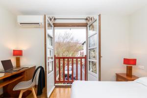 a bedroom with a bed and a desk and a window at Hôtel Lastiry in Sare