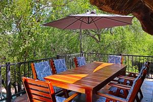 einen Holztisch und Stühle mit Sonnenschirm auf einer Terrasse in der Unterkunft Kruger Park Hostel in Marloth Park