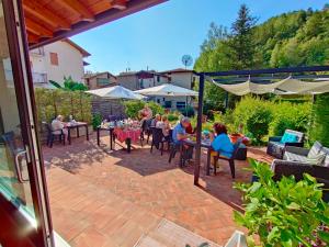 un groupe de personnes assises à des tables sur une terrasse dans l'établissement Bed&Breakfast Angela, à Clusone