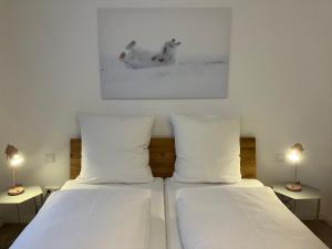 2 camas con almohadas blancas en una habitación con 2 lámparas en Alpenflair Ferienwohnungen Schulz, en Oberstdorf