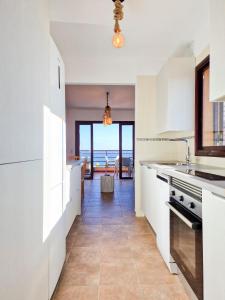 une cuisine avec des placards blancs et une vue sur l'océan. dans l'établissement MEDANO4YOU The Ocean Terrace Penthouse, à El Médano