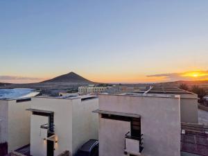 - une vue sur un bâtiment avec le coucher du soleil en arrière-plan dans l'établissement MEDANO4YOU The Ocean Terrace Penthouse, à El Médano