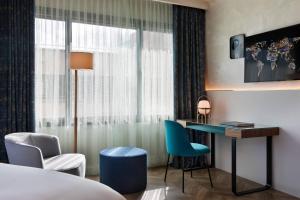 a hotel room with a bed and a desk and chairs at Renaissance Barcelona Hotel in Barcelona