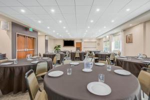 a conference room with tables and chairs and a screen at Days Inn & Suites by Wyndham Lindsay in Lindsay