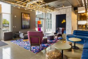 a lobby with a blue couch and chairs and tables at Aloft Austin Airport in Austin