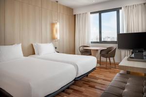 マラガにあるAC Hotel Málaga Palacio by Marriottのベッド2台とテーブルが備わるホテルルームです。