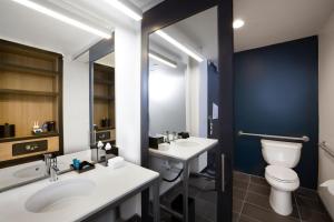 a bathroom with two sinks and a toilet and a mirror at Aloft Austin Airport in Austin