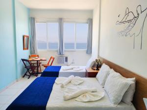 Habitación de hotel con 2 camas, escritorio y ventana en Studio na Praia Vista Total TC1202, en Río de Janeiro