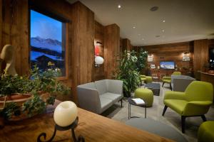 ein Wartezimmer mit Stühlen und Pflanzen und einem großen Fenster in der Unterkunft Hotel Bernina in Livigno