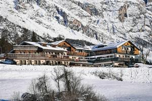 a large building in the snow in front of a mountain at Rosapetra SPA Resort - Small Luxury Hotels of the World in Cortina dʼAmpezzo