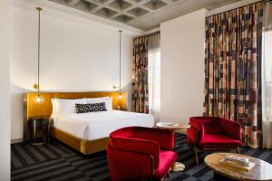 a hotel room with a bed and two red chairs at Hotel Indy, Indianapolis, a Tribute Portfolio Hotel in Indianapolis