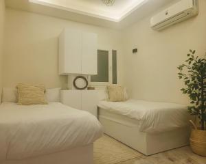a white room with two beds and a plant at Selena Bay Resort - Luxury 2 Bed Apt with Private Beach in Hurghada