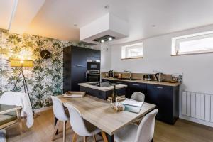 a kitchen and dining room with a wooden table and chairs at Le 37 - Maison 2 chambres en bord de mer in Saint-Cast-le-Guildo