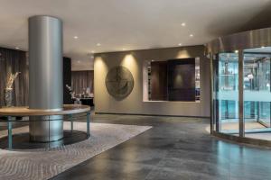 um lobby com um relógio na parede e uma mesa em AC Hotel La Finca by Marriott em Pozuelo de Alarcón