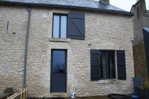 una casa con persianas negras y una ventana en La Maison, en La Chapelle-Saint-Martin-en-Plaine