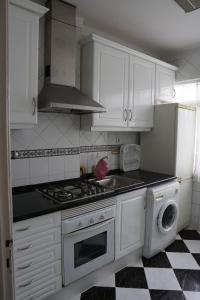 La cuisine est équipée de placards blancs, d'une cuisinière et d'un lave-vaisselle. dans l'établissement Herois Apartment, à Damaia