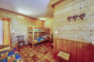 a bedroom with a bunk bed and a wooden wall at Chalet Melody in La Toussuire