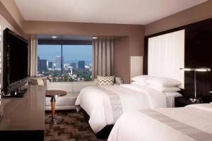 a hotel room with three beds and a large window at Beverly Hills Marriott in Los Angeles