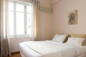 a bedroom with a bed with white sheets and a window at Hadrians Den in Heart of Plaka by JJ Hospitality in Athens